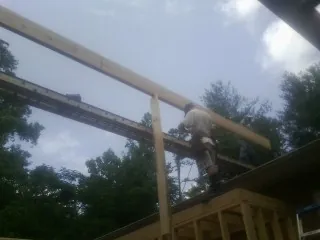 Carpenter setting a ridge beam over a new addition frame — Ice Dam Removal by Roofing Brothers in Parlier