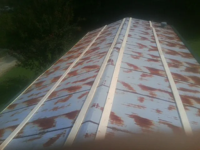 Rusted metal roof panels with new wood purlins before replacement — Storm Damage Roof Repair in Parlier by Roofing Brothers