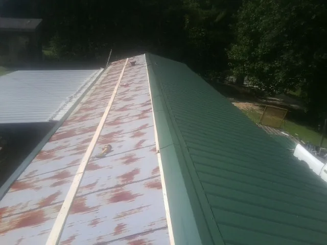 Old rusted panels beside newly installed green metal roofing — Wind Damage Roof Repair by Roofing Brothers in Parlier
