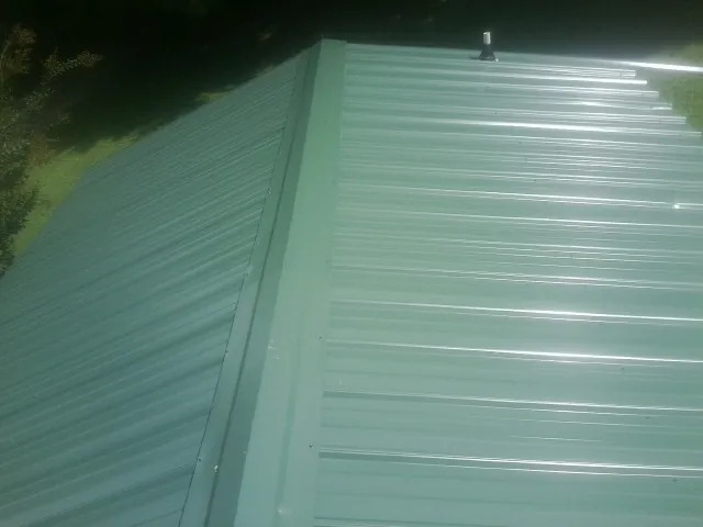New green metal panels meeting at the ridge of a roof — Flat Roof Repair work by our crew in Parlier