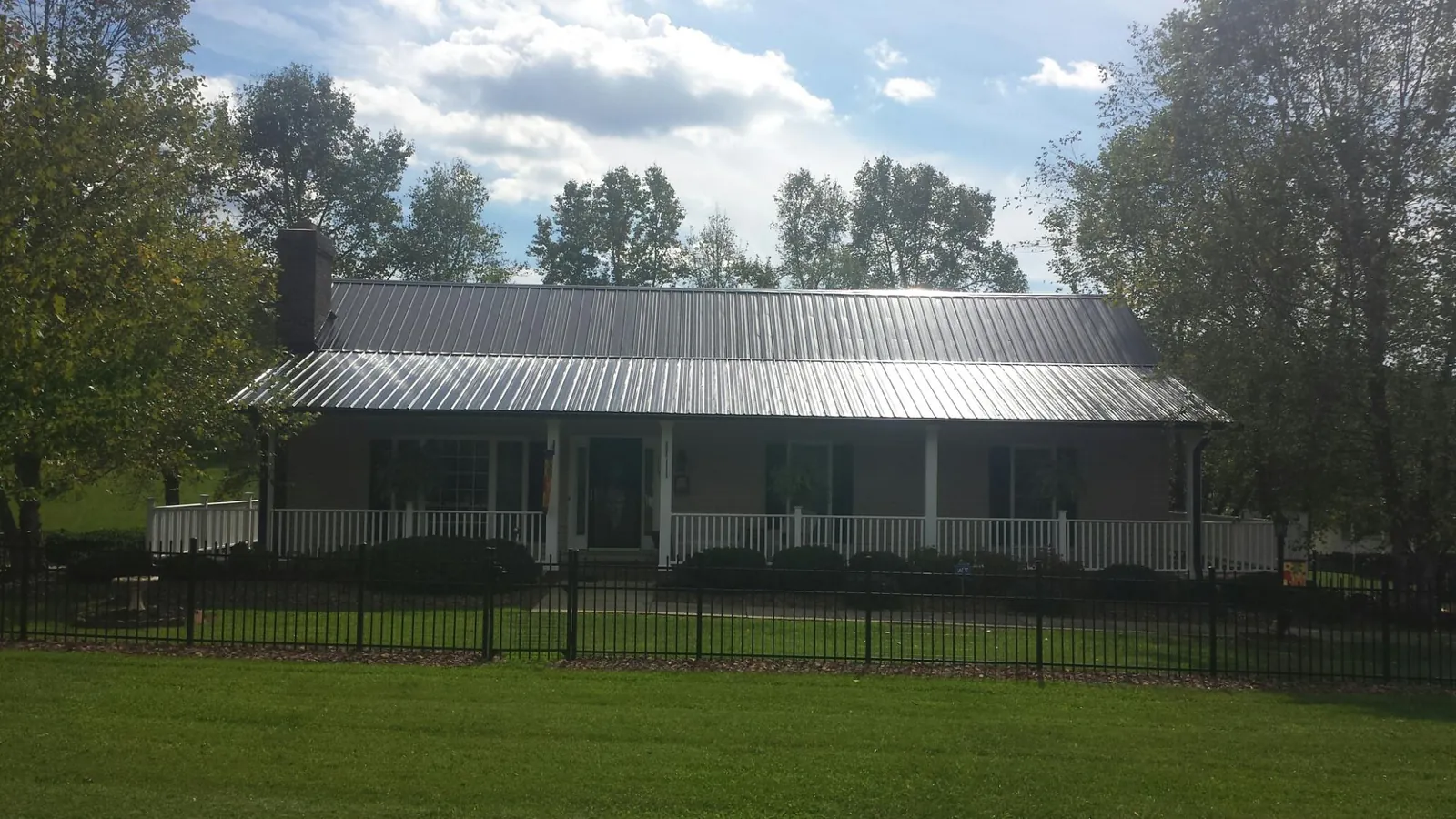 Gray metal roof on a brick ranch with a full width front porch — Gutter Guard Installation work by our crew in Parlier