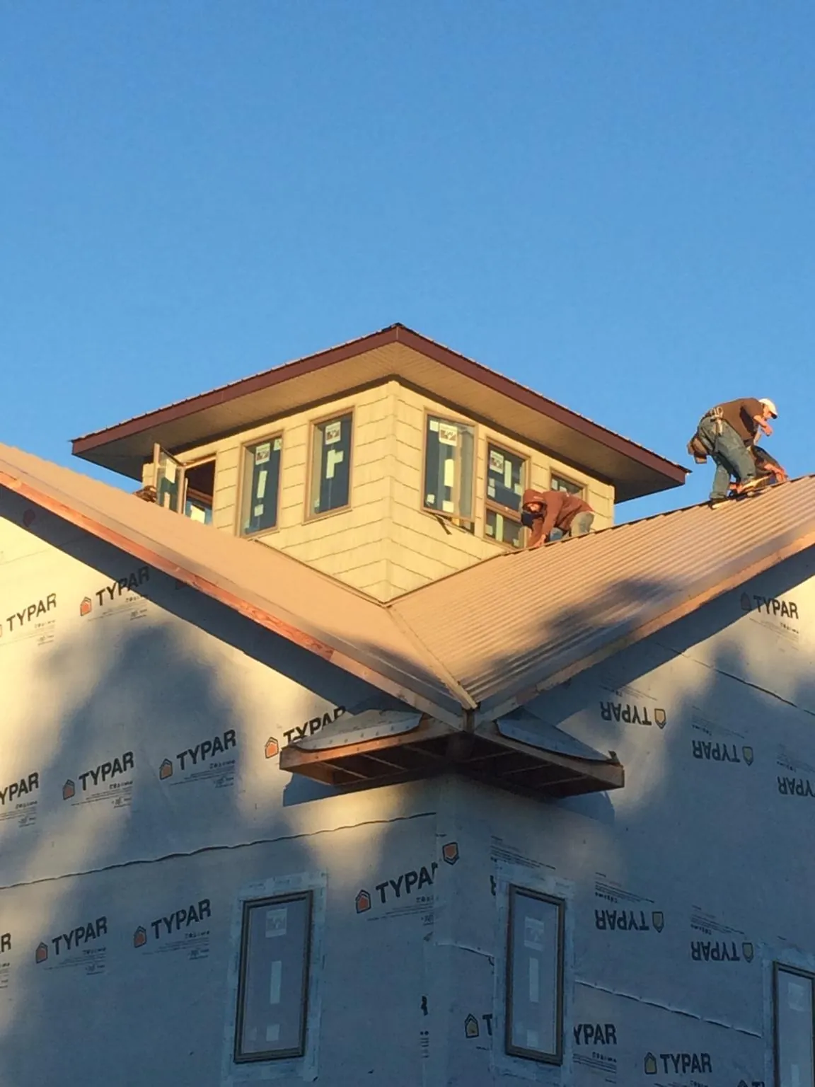 Roofers working around a rooftop cupola on a new metal roof at sunset — Roof Waterproofing in Parlier by Roofing Brothers